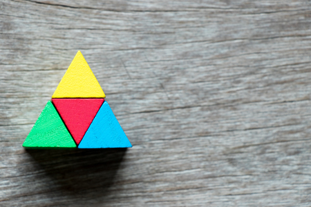 Multi color toy block compound as triangle shape on wood backgroundの写真素材