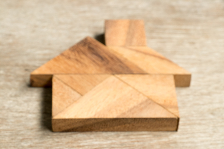 Defocused tangram puzzle in home shape on wood backgroundの写真素材