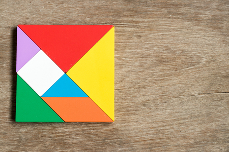 Colorful tangram puzzle in square shape on wood backgroundの写真素材