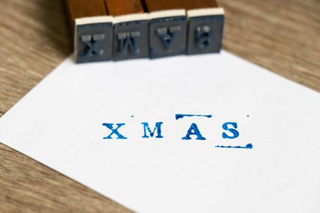 Blue wording xmas on white paper with wood block stamp on wood backgroundの写真素材