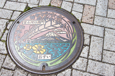 KAWAGUCHIKO, JAPAN - April 24, 2017: Metal pipe cap on street that design is mount Fuji, bridge, sakura blossom and Kawaguchiko lakeのeditorial素材