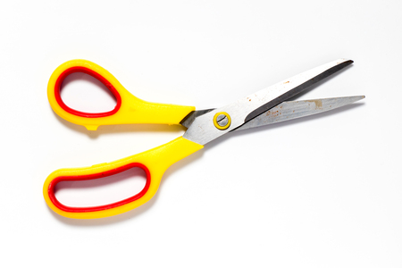 Metal scissors with yellow and red plastic holder on white backgroundの写真素材