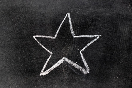 White chalk hand drawing in star shape on blackboard backgroundの写真素材