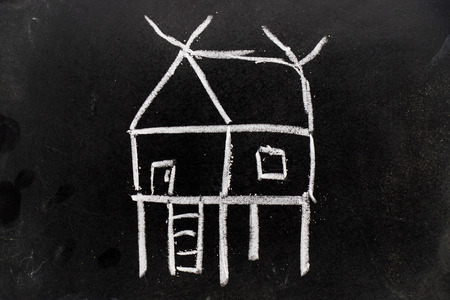 CHalk hand drawing as home shape on black board backgroundの写真素材