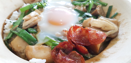 Closed up of baked rice with chinese sausage, 

straw mushroom and fried egg in clay potの写真素材