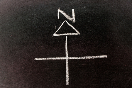 White chalk drawing in compass arrow, north direction shape on black board backgroundの写真素材