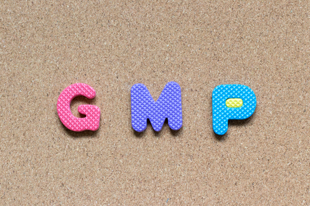 Color foam alphabet in word GMP (Abbreviation of good manufacturing practice) on cork board backgroundの写真素材