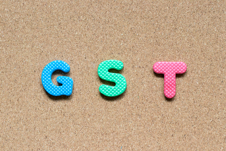 Color foam alphabet in word GST (Abbreviation of Goods and Service Tax)  on cork board backgroundの写真素材