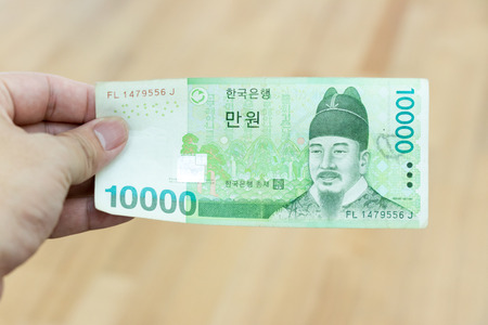 Business man hold south korea banknote 10000 korean won on wood backgroundの写真素材