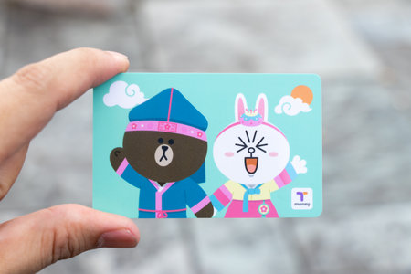 Seoul, South Korea- Sep 4, 2018  : Traveller hand hold t money card with line cartoon character on blur background. T Money is a prepaid card for travelling with train, bus and shopping in South Koreaのeditorial素材