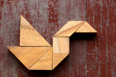 Tangram puzzle in swan shape on red old wood backgroundの写真素材