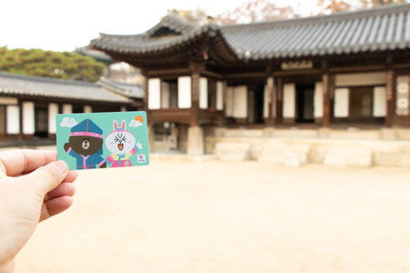 Seoul, South Korea- Sep 7, 2018  : Traveller hand hold t money card with line cartoon character on defocused Korean palace background. T Money is a prepaid card for travelling with train, bus and shopping in South Koreaのeditorial素材