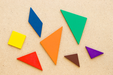 Color tangram in piece wait to complete shape on wood backgroundの写真素材
