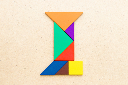 Tangram puzzle in alphabet letter I shape on wood backgroundの写真素材