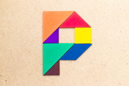 Tangram puzzle in alphabet letter p shape on wood backgroundの写真素材