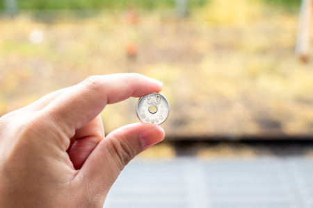 Man hold japanese coin 50 yen on blurred background