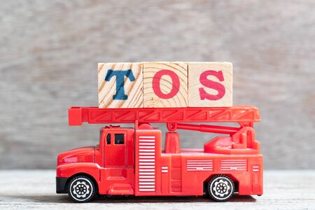 Red fire truck hold letter block in word TOS (abbreviation of Terms Of Service) on wood backgroundの写真素材