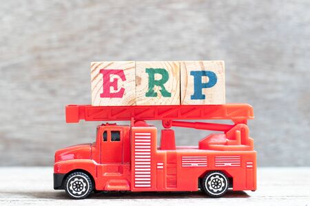 Red fire truck hold letter block in word ERP (Abbreviation of Enterprise Resource Planning) on wood backgroundの写真素材