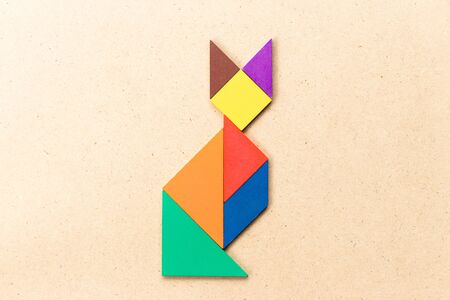 Color tangram puzzle in sitting cat shape on wood backgroundの写真素材