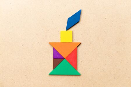 Color tangram puzzle in candle with flame shape on wood backgroundの写真素材