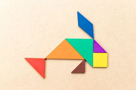 Color tangram puzzle in fish shape on wood backgroundの写真素材