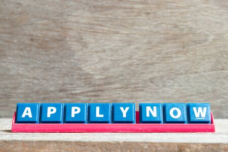 Tile letter on red rack in word apply now on wood backgroundの写真素材