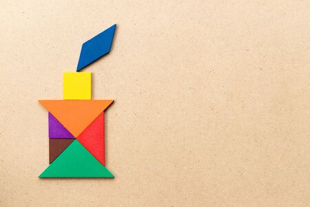 Color tangram puzzle in candle with flame shape on wood backgroundの写真素材