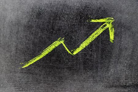 Green chalk draw as upward arrow graph on black board background (Concept for sale, profit, cost of company in uptrend)の写真素材