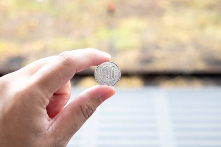 Man hold japanese coin 100 yen on blurred backgroundの写真素材
