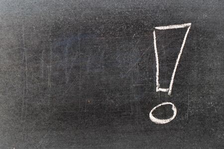 White color chalk hand drawing in exclamation mark with blank space shape on blackboard backgroundの写真素材