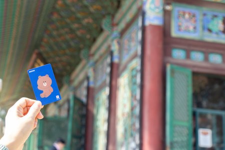 Seoul, South Korea- Oct 20, 2019 : Traveller hand hold t money card with brown line cartoon character on defocused Korean temple background.のeditorial素材
