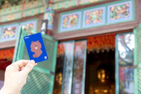 Seoul, South Korea- Oct 20, 2019 : Traveller hand hold t money card with brown line cartoon character on defocused Korean temple background.のeditorial素材