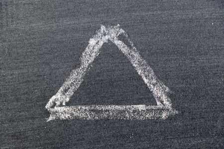 White color chalk hand drawing in triangle shape on black board backgroundの写真素材