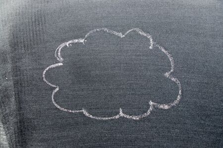 White color chalk hand drawing in cloud or blank speech bubble shape on black board backgroundの写真素材
