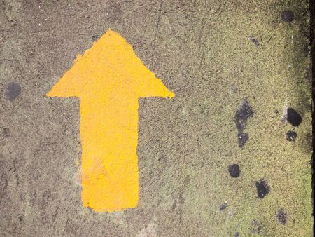 Yellow arrow painting on gray concrete background