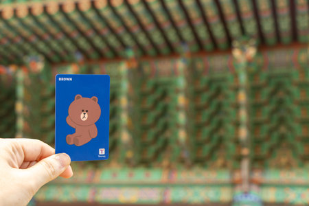 Seoul, South Korea- Oct 20, 2019 : Traveller hand hold t money card with brown line cartoon character on defocused Korean temple background.のeditorial素材