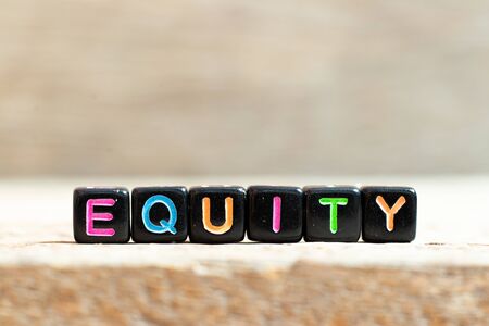 Black bead with color letter in word equity on wood background