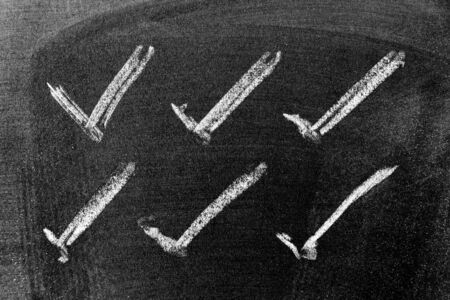 White color chalk hand drawing in set of check mark shape on black board background