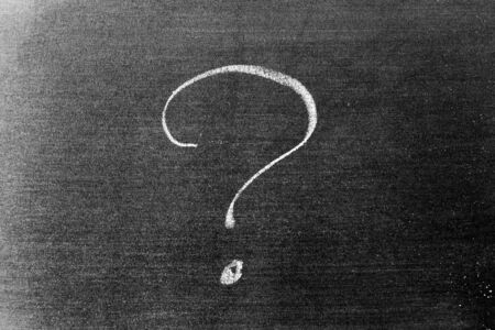 White color chalk hand drawing in question mark shape on blackboard background