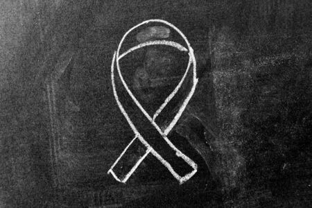 White color chalk drawing as black ribbon shape on black board background (Concept for symbol of remembrance or mourning)の写真素材