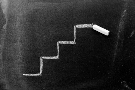 White color chalk hand drawing in staircase shape on black board backgroundの写真素材