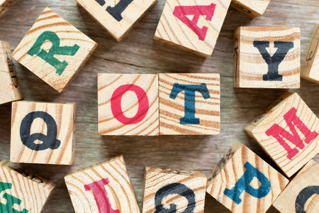 Alphabet letter block in word OT (abbreviation for overtime) with another on wood background