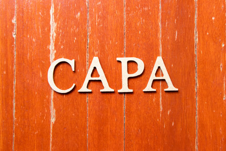 Alphabet letter in word CAPA (abbreviation of corrective action and preventive action) on old red color wood plate backgroundの写真素材