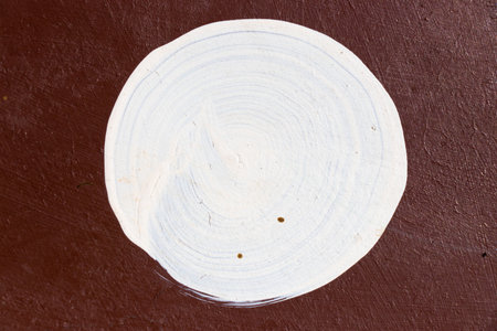 White color painting in round shape on brown concrete textured backgroundの写真素材