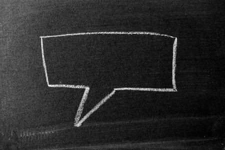 White color chalk hand drawing in square bubble speech shape with blank space on blackboard or...