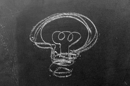White color chalk hand drawing in light bulb shape on blackboard or chalkboard background (Concept...