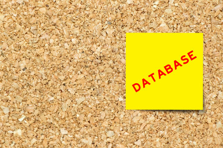 Yellow note paper with word database on cork board background with copy spaceの写真素材