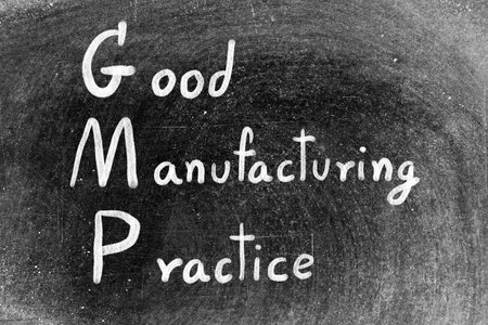 White hand writing in word GMP good manufacturing practice on black board backgroundの写真素材