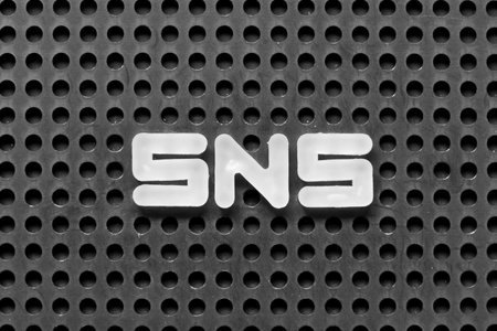 White alphabet letter in word SNS (abbreviation of Social Networking Site or sorry not sorry) on black pegboard backgroundの写真素材