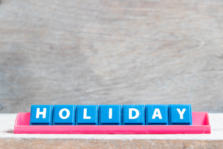 Tile alphabet letter with word holiday in red color rack on wood backgroundの写真素材